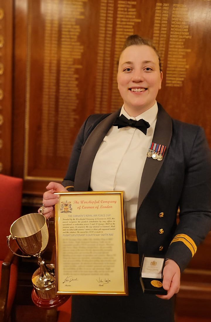 Photo: Flight Lieutenant Smith from RAF Brize Norton standing in Mess dress uniform with her certificate, cup and medal in her hands